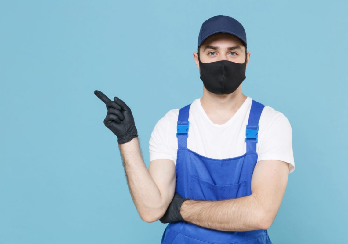 Delivery man in cap tshirt coveralls uniform sterile face mask gloves isolated on blue background studio. Guy employee courier Service quarantine pandemic coronavirus virus covid-19 2019-ncov concept